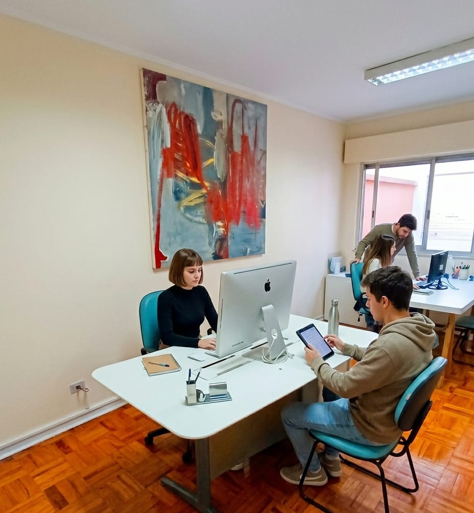 Escritório privativo da playINwork com mesas brancas, cadeiras ergonômicas e quadro decorativo